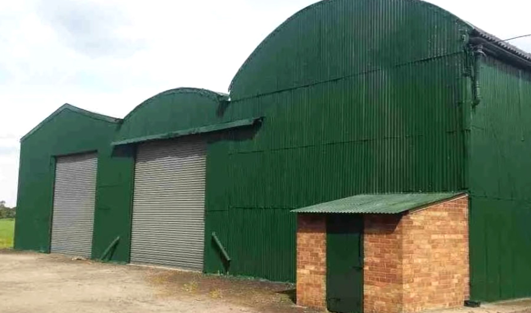 Deep green corrugated hay barn with shutter doors
